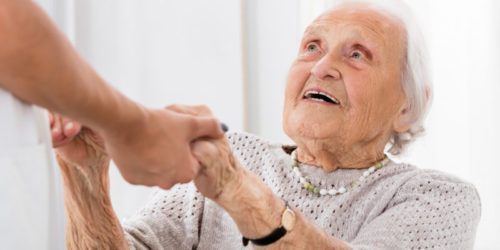 Happy Senior Patient Holding Hands Of Female Doctor In Hospital