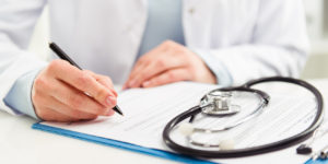 Young woman physician with stethoscope prescribing treatment